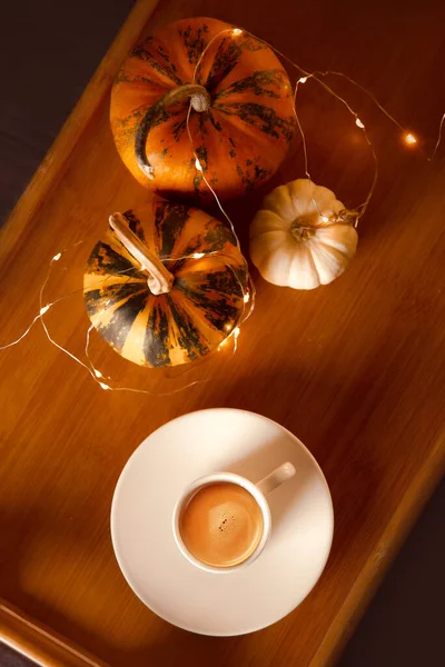 pumpkin coffee for winter mood with small decorative pumpkins on wooden tray in bed