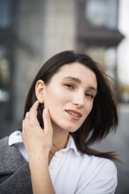 Kadın, sıcak bahar havasında şehir caddesinde yürüyen kameraya bakıyor.