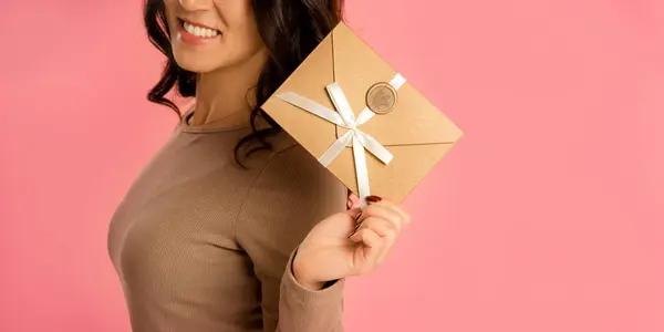 happy woman holding Gift Certificate on pink background