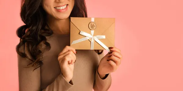stylish woman enjoy Gift Certificate, festive mood in holidays on pink studio background