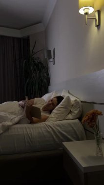 Kitap okuyan kadın akşamları yatağında uzanıyor.