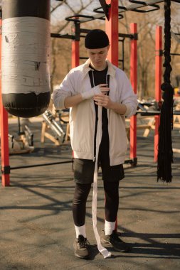 Genç çocuk dışarıda boks yapmadan önce elini sarar.