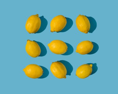 Parlak pastel mavi arka planda taze sarı limonlarla yapılmış yaz çerçeve deseni. Keskin gölgeli parlak güneş ışığı konsepti.