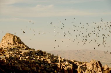 Gökyüzünde uçan güvercinler, arka planda bir Greme / Cappadocia şehri