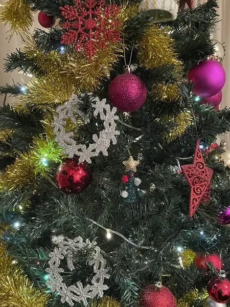 Bu görüntüdeki Noel 'in ihtişamına bakın. Renkli süslerle süslenmiş güzel bir ağaç, parıldayan ışıklar ve tepesinde bir yıldız. Sıcak, şenlikli bir atmosfer ve hediyelerle çevrelenmiş, tatil sezonunun özünü yakalıyor.