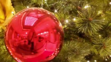 Büyük salonda kırmızı ve altın çiçeklerle süslenmiş Noel ağacı, toplar, ışıklar ve çelenkler. 