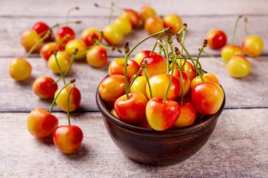 Gri ahşap arka planda yaprakları olan sarı, taze kiraz. Lezzetli kiraz