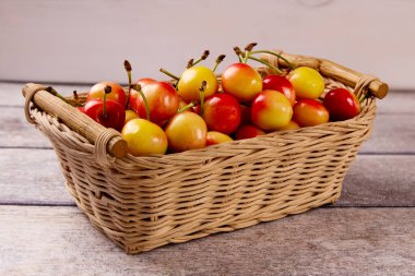 Gri ahşap bir arka planda sepetteki sarı taze kiraz. Lezzetli kiraz