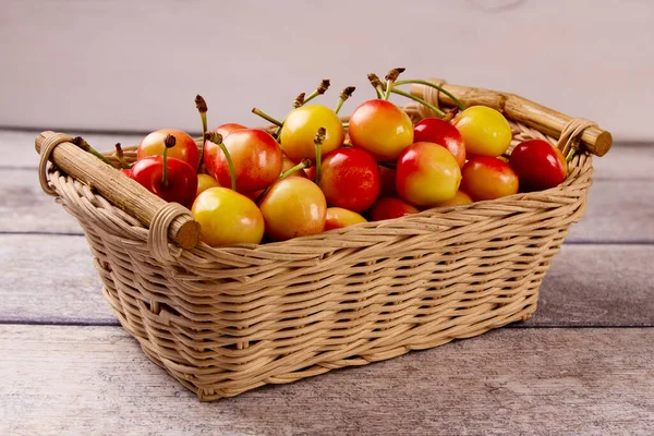 Gri ahşap bir arka planda sepetteki sarı taze kiraz. Lezzetli kiraz