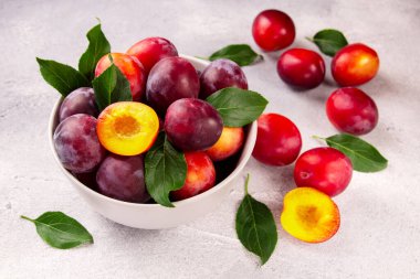 Gri arka planda olgun sulu eriklerle dolu bir kase, doğanın armağanları..