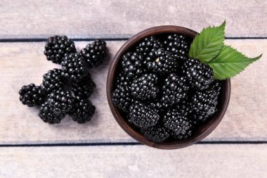 Açık Ahşap Arkaplan 'da Yapraklar Kil Kasesinde Olgun Blackberry' ler. BlackBerry 'nin Tahta Masadaki Kil Kasesi Fotoğrafı.