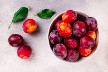 Gri arka planda olgun sulu eriklerle dolu bir kase, doğanın armağanları..