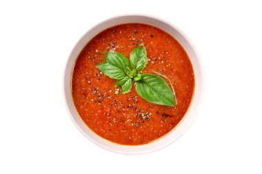 Beyaz arka planda fesleğenli ve baharatlı ev yapımı domates kremalı çorba.