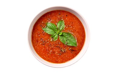 Beyaz arka planda fesleğenli ve baharatlı ev yapımı domates kremalı çorba.