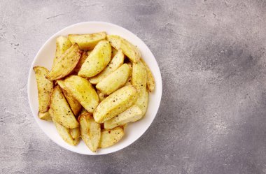 Kızarmış patates. Gri bir taşın üzerinde baharatlarla pişirilmiş patates dilimleri.. 