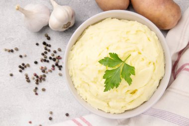Patates püresi, tereyağlı ve taze maydanozlu gri taştan arka planda beyaz bir kasede.