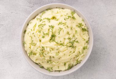 Patates püresi, tereyağlı ve taze maydanozlu gri taştan arka planda beyaz bir kasede.