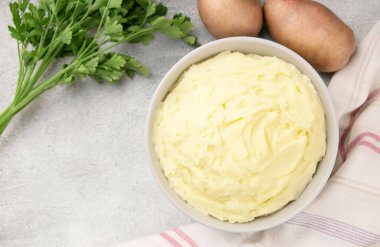 Geleneksel ev yapımı, gri beton arka planda beyaz kasede patates püresi. Sağlıklı yemek.