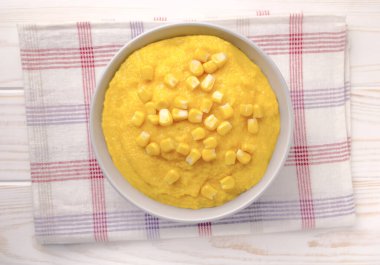 Açık gri mutfak masasında seramik tabakta mısır lapası. Yulaf lapası ya da baharatlı krema çorbası..