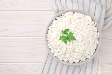 Hafif ahşap arka planda bir kasede çiftlik peyniri. Maydanozlu süzme peynir. Kasedeki süzme peynir..