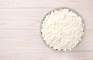 Hafif ahşap arka planda bir kasede çiftlik peyniri. Kasedeki süzme peynir..