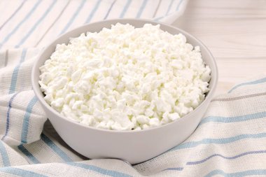 Hafif ahşap arka planda bir kasede çiftlik peyniri. Kasedeki süzme peynir..