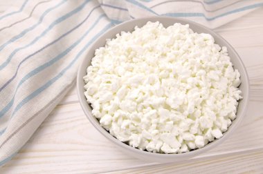 Hafif ahşap arka planda bir kasede çiftlik peyniri. Kasedeki süzme peynir..