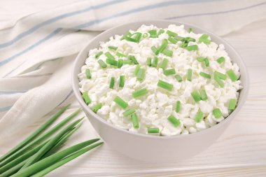 Hafif ahşap arka planda bir kasede çiftlik peyniri. Yeşil soğanlı süzme peynir. Kasedeki süzme peynir..