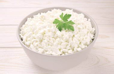 Hafif ahşap arka planda bir kasede çiftlik peyniri. Maydanozlu süzme peynir. Kasedeki süzme peynir..