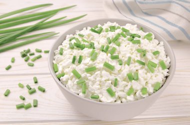 Hafif ahşap arka planda bir kasede çiftlik peyniri. Yeşil soğanlı süzme peynir. Kasedeki süzme peynir..