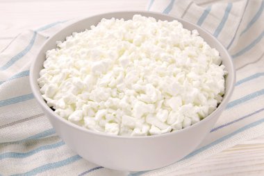 Hafif ahşap arka planda bir kasede çiftlik peyniri. Kasedeki süzme peynir..