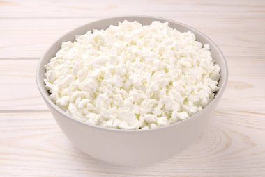 Hafif ahşap arka planda bir kasede çiftlik peyniri. Kasedeki süzme peynir..