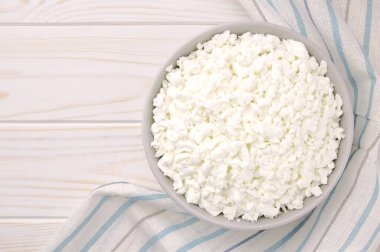 Hafif ahşap arka planda bir kasede çiftlik peyniri. Kasedeki süzme peynir..