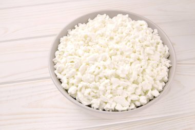 Hafif ahşap arka planda bir kasede çiftlik peyniri. Kasedeki süzme peynir..