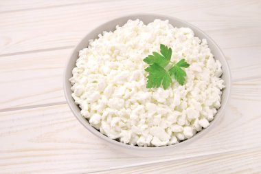 Hafif ahşap arka planda bir kasede çiftlik peyniri. Maydanozlu süzme peynir. Kasedeki süzme peynir..