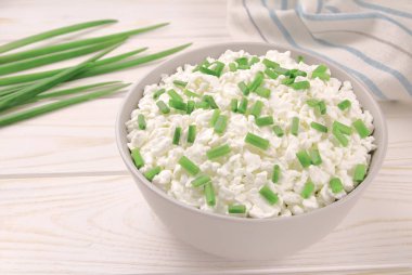 Hafif ahşap arka planda bir kasede çiftlik peyniri. Yeşil soğanlı süzme peynir. Kasedeki süzme peynir..