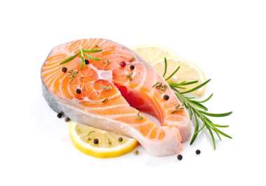 Beyaz arka planda biberiyeli, limonlu ve biberli taze somon bifteği.