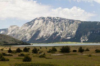 Dağların eteğinde gölü olan geniş bir dağ manzarası