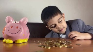 Huzursuz anaokulu çocuğunun yüz ifadesi, madeni paraları sayan takım elbiseli çocuk. Yatırım konsepti ve çocuk tasarrufu. Yüksek kalite 4k görüntü