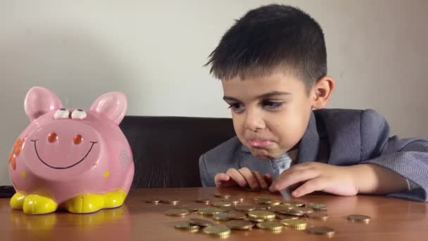 可爱的孩子 穿着西装 满脸愁容的男孩看着小猪银行和硬币 负投资回报 高质量的4K镜头 — 图库视频影像