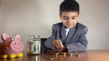 Açgözlü çocuk işadamı. Anaokulunda kumbarası olan, kavanoz biriktiren ve evinin anahtarıyla masaya bozuk para koyan bir çocuk. Gayrimenkul yatırım kavramı. Yüksek kalite 4k görüntü