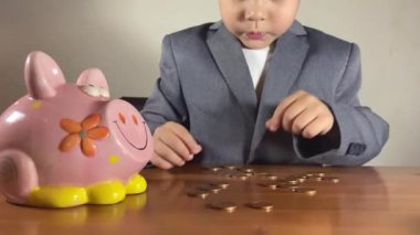 Odaklanmış anaokulu çocuğu, takım elbiseli çocuk paraları sayıyor. Yatırım konsepti ve çocuk tasarrufu. Yüksek kalite 4k görüntü