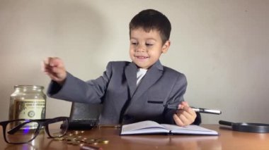 Bozuk para sayan ve kavanozu birikimlerle dolduran sevimli bir çocuk. Hesap makinesi kullanarak ve günlüğe yazarak. Finansal planlama kavramı. Yüksek kalite 4k görüntü