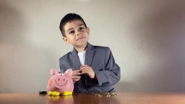 Takım elbiseli şirin çocuk parayı ısırıyor. Çocuk tasarrufu ve zenginlik kavramının büyümesi. Yüksek kalite 4k görüntü