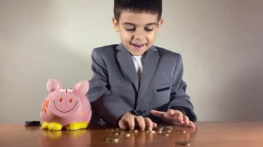Takım elbiseli aç gözlü çocuk bozuk para toplayıp oynuyor. Yatırımdan iyi kazanç. Yüksek kalite 4k görüntü