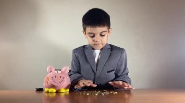 Takım elbiseli aç gözlü çocuk bozuk para toplayıp oynuyor. Yatırımdan iyi kazanç. Yüksek kalite 4k görüntü