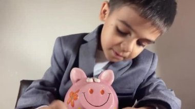 Kumbarası olan takım elbiseli sevimli çocuk. Çocuk tasarrufu ve zenginlik kavramının büyümesi. Yüksek kalite 4k görüntü