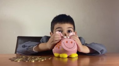 Odaklanmış anaokulu çocuğu, takım elbiseli çocuk paraları sayıyor. Yatırım konsepti ve çocuk tasarrufu. Yüksek kalite 4k görüntü