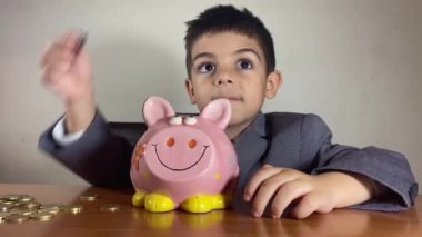 Odaklanmış anaokulu çocuğu, takım elbiseli çocuk paraları sayıyor. Yatırım konsepti ve çocuk tasarrufu. Yüksek kalite 4k görüntü