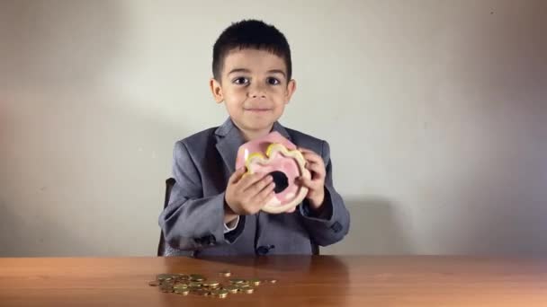 穿着西装的学龄前男孩笑着摇动着小猪银行 儿童储蓄概念 高质量的4K镜头 — 图库视频影像
